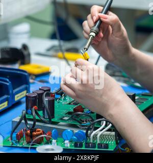 Perm, Russia - May 23, 2024: female worker`s hand soldering of electronic circuit boards close-up Stock Photo